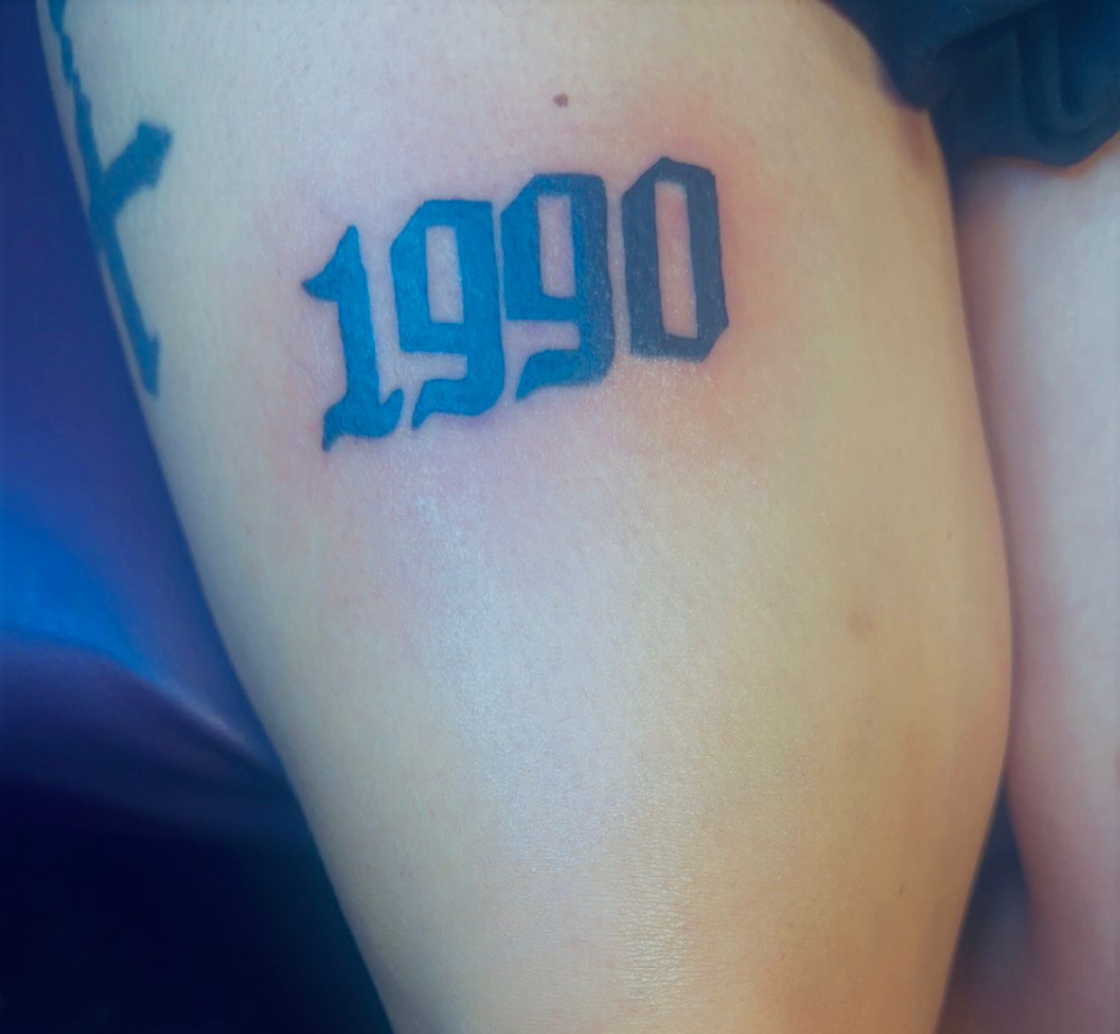 Tatouage lettering 1990 typographie gothique cuisse Hakuna Tattoo Arpajon