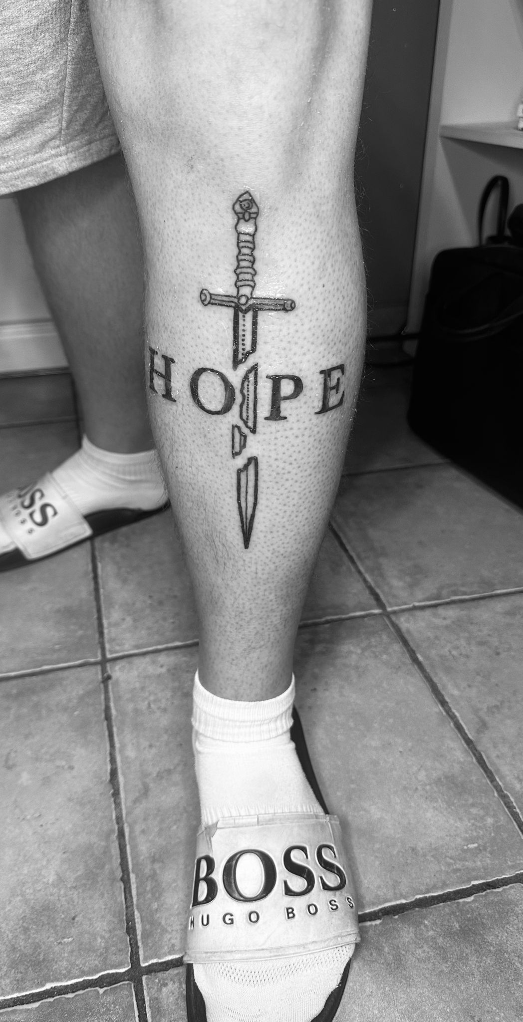 Tatouage lettering Hope avec epee gothique mollet Hakuna Tattoo